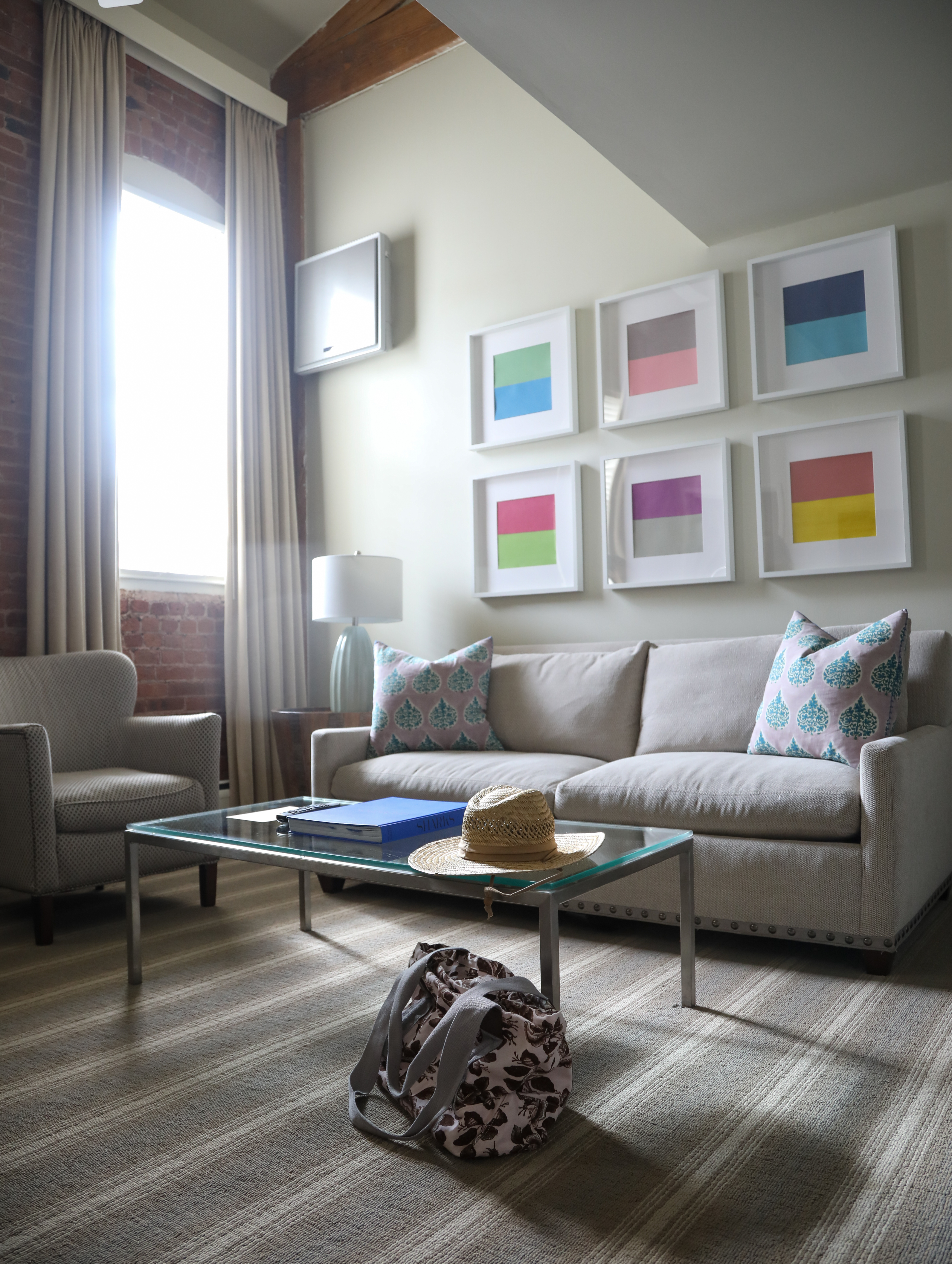 A lobby with a sofa, coffee table, chair and artwork